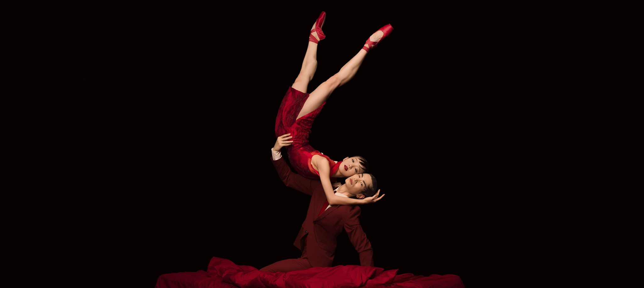 Male and female ballet dancers in intertwined pose on stage